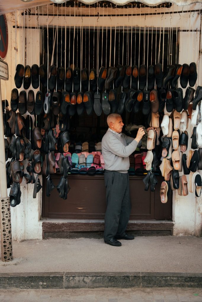 local man hanging shoes in tetouan medina